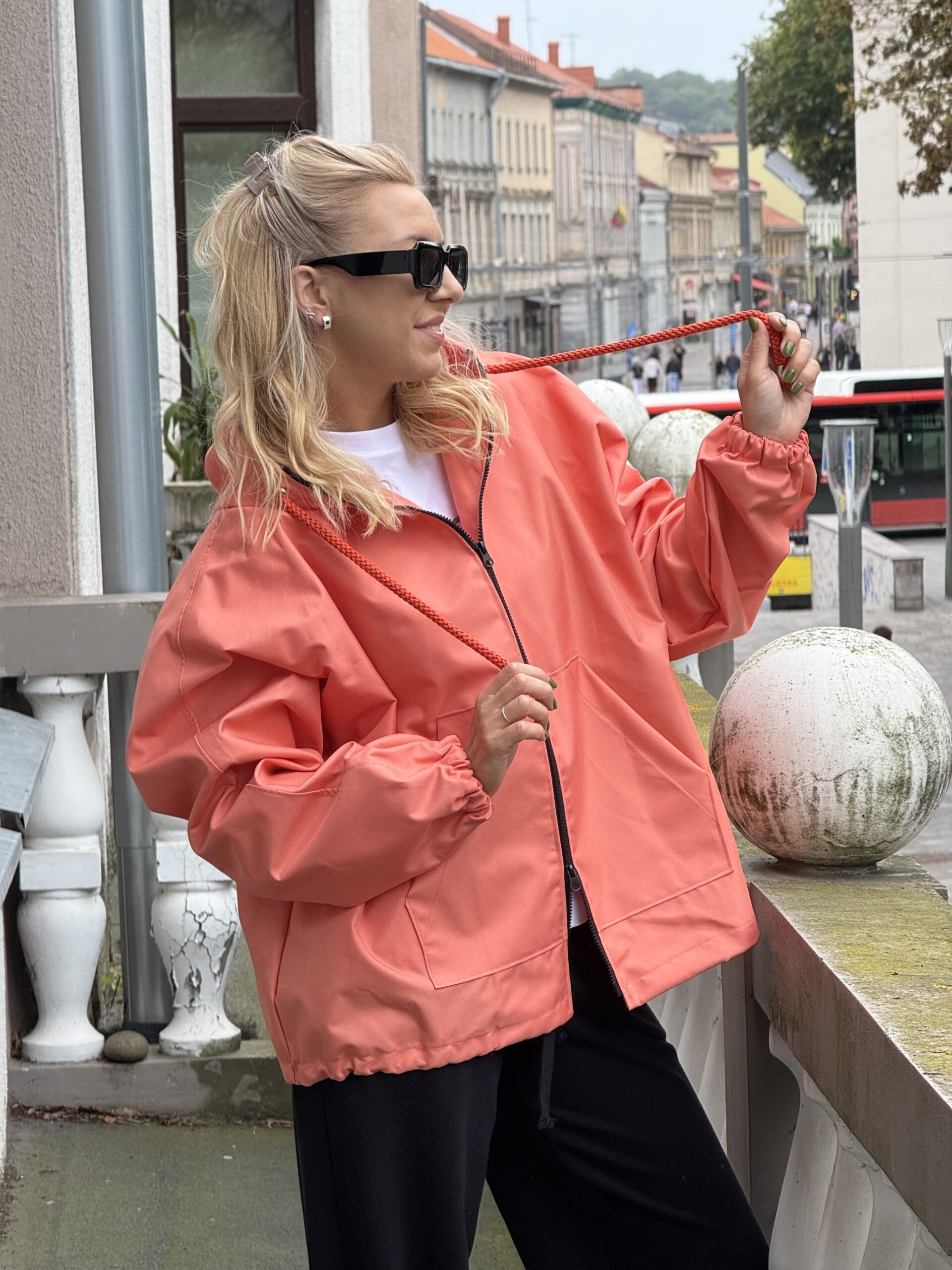 Koralinis trumpas lietpaltis su oranžiniais raišteliais